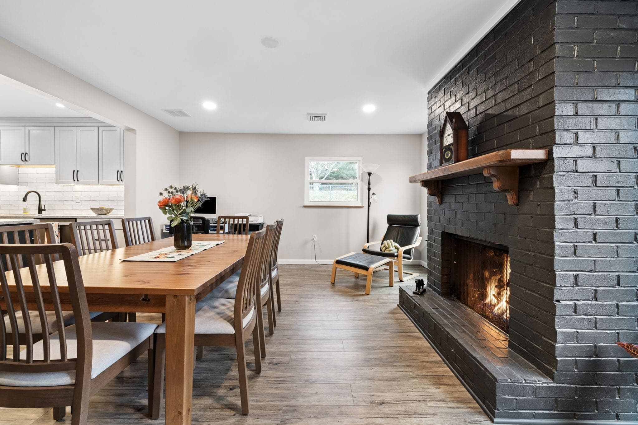 Dining room with a painted black brick fireplace and patio doors in a whole-home renovation on Hereford Drive in Oakdale, PA, built by Integrated Contracting & Renovations